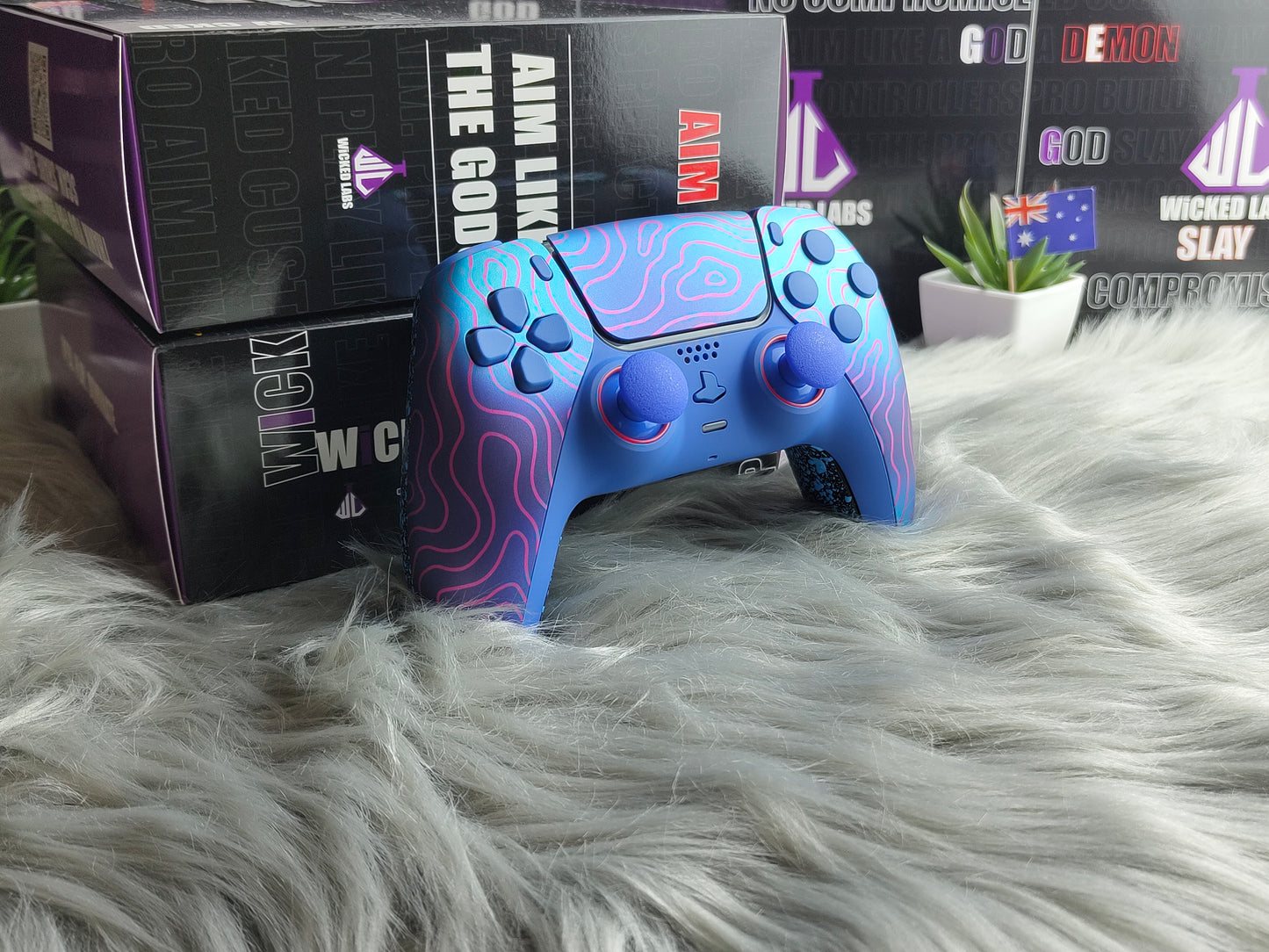 Blue gaming controller with purple accents on a fluffy white surface, with boxes in the background.